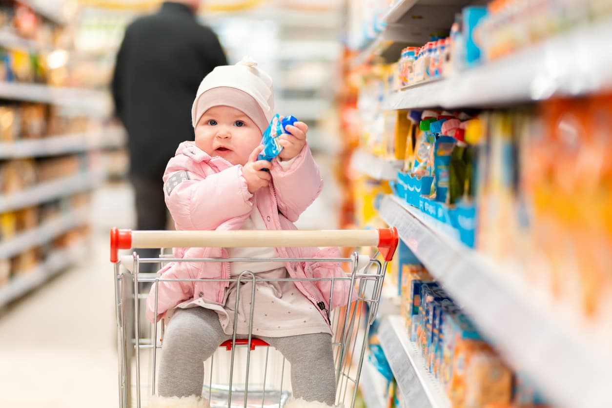 baby in a grocery store cart in a food aisle